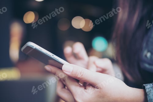 Preview: A business woman holding and touching smart phone in modern cafe