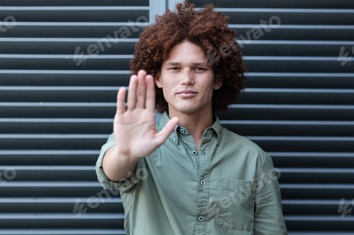 Vista previa: Portrait of mixed race man holding hand making a stop gesture
