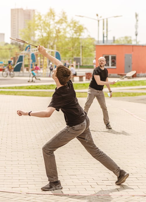 Preview: dad with his teenage son playing badminton in the yard