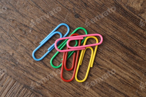 Preview: Many colorful paper clips on wooden table, top view