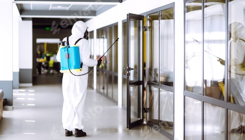 Preview: Disinfecting of office to prevent COVID-19, Man in protective hazmat suit with spray chemicals.