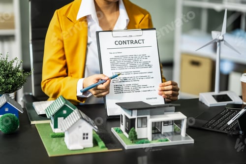 Preview: A businesswoman is reviewing contract papers at her desk in a sustainable house and condo