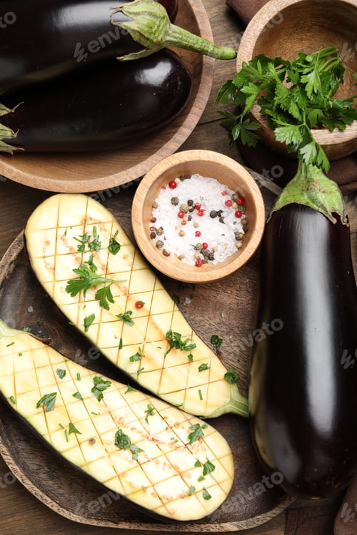 Preview: Halves of fresh eggplant, whole ones, spices and parsley on wooden table, flat lay