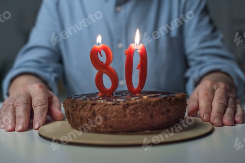 Vista previa: Vista de cerca de un hombre mayor celebrando su 80 aniversario con pastel y velas de números encendidos
