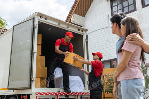 Preview: Young couple checks with two movers unloading boxes and furniture from a pickup truck