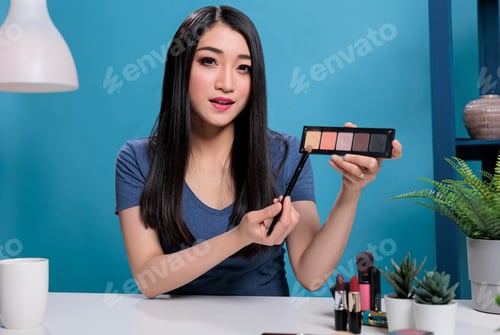 Preview: Social media influencer holding make up palette showing at camera