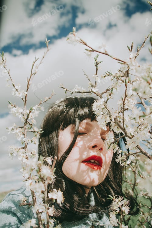 Preview: Beautiful young woman posing near spring flowers