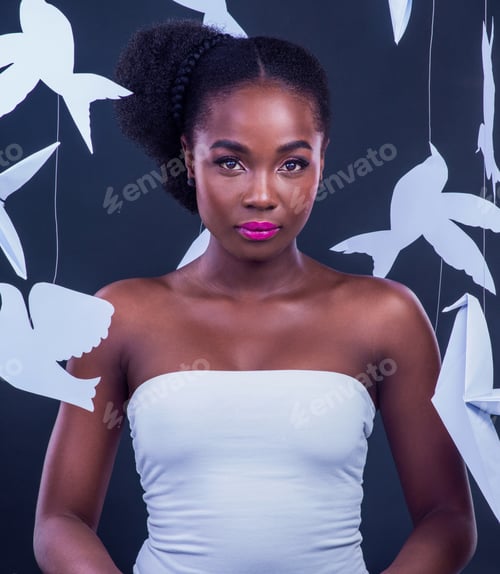 Preview: Studio portrait of a beautiful young woman posing with paper birds against a black background