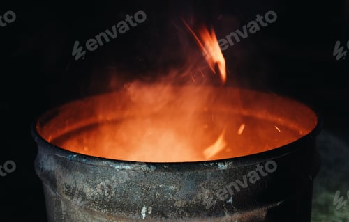 Preview: fire burning inside a metal barrel at night