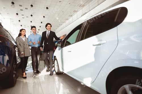 Preview: Seller Guy Helping Family Couple Choose Car In Dealership Showroom