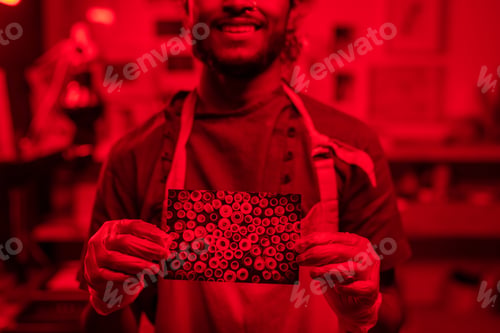 Preview: Gloved hands of happy young photographer holding photo of threads
