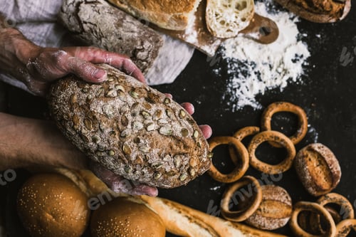 Preview: Baker man holding a rustic organic loaf of bread in his hands