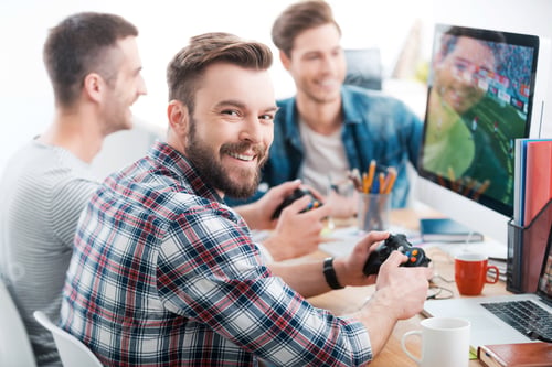 Preview: Work hard play hard. Three young men playing computer games while sitting at the desk in the office