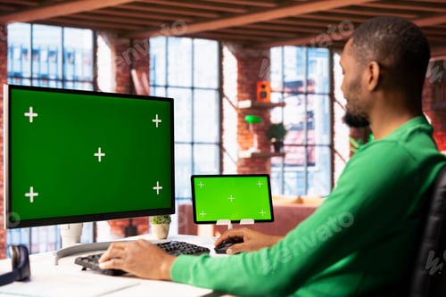 Preview: Man in home office using chroma key PC display and tablet to work