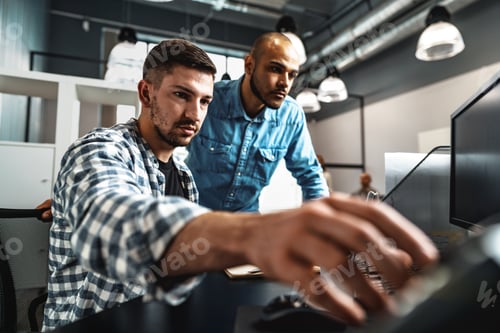 Preview: Two young men working together on a new business project in office