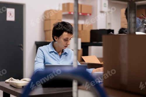 Preview: Storehouse manager sitting at desk table looking at cargo stock before start preparing clients