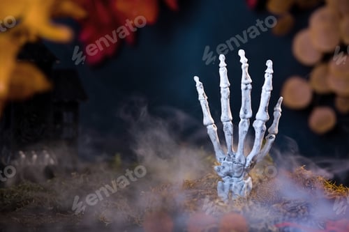 Preview: Skeleton hand emerges from moss surrounded by misty smoke against backdrop of fall leaves.