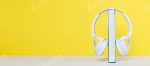 Aperçu: Audio book concept with modern white headphones and hardcover book on a yellow background.