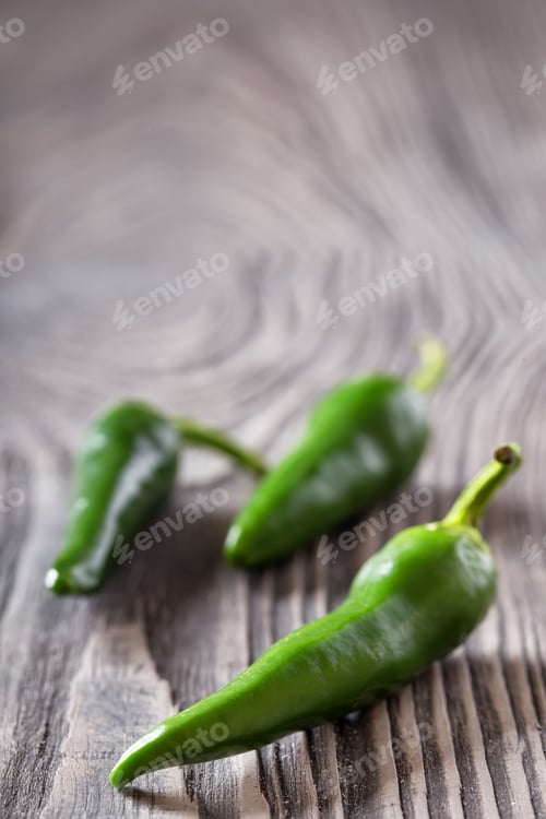 Preview: Three green hot peppers on a wooden table
