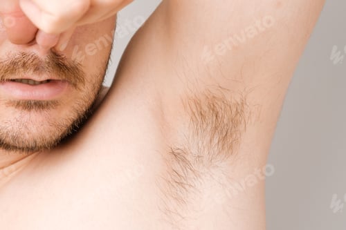 Preview: Close up of man armpit with long unshaved hair and pinching nose from sweaty bad smell
