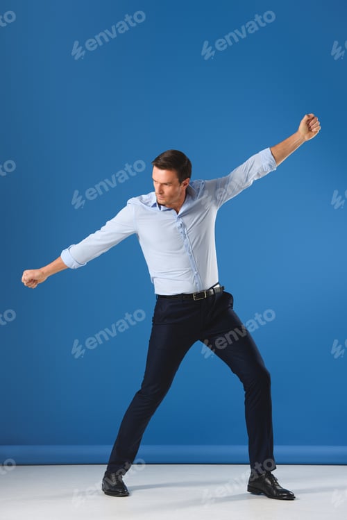 Preview: full length view of handsome man posing and looking away on blue