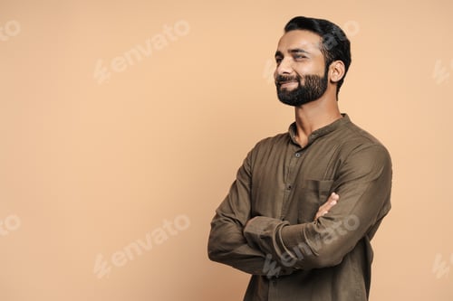 Preview: Confident indian businessman smiling with crossed arms looking away isolated on beige background