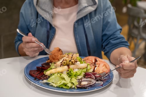 Preview: Mature Caucasian woman enjoying a mixed salad of fresh vegetables, healthy eating