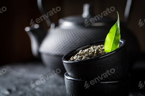 Preview: Closeup of leaf green tea in teacup on black rock