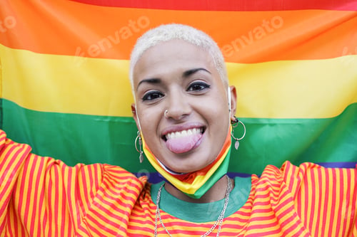 Preview: Beautiful young lesbian woman with lgbt rainbow flag at gay pride parade
