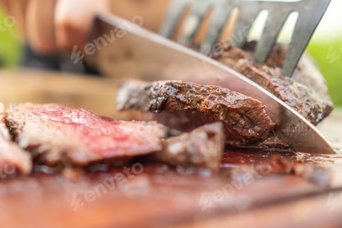 Preview: Man using knife to cut meat in the garden