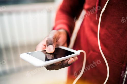 Preview: A close-up of black man runner with smartphone and earphones in a city.
