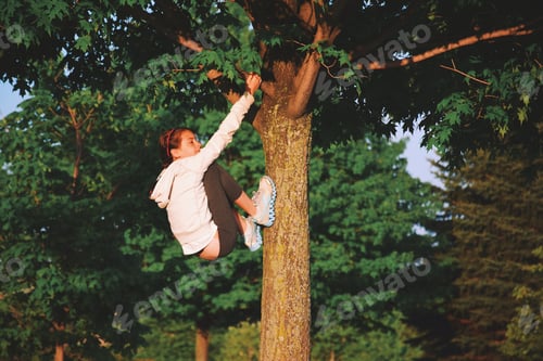 Preview: Young teenage girl is trying to climb a tree