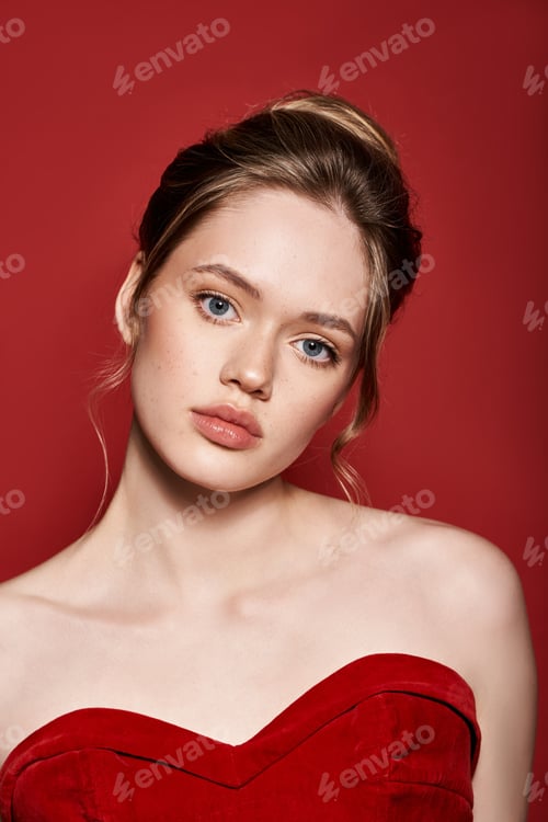 Preview: Elegant young woman striking a chic pose against a vibrant red backdrop in spring fashion