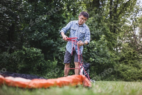 Preview: Mature man putting up tent