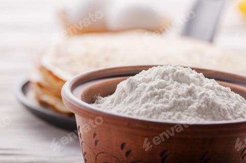 Preview: Stack of French crepes in frying pan on wooden kitchen table wit