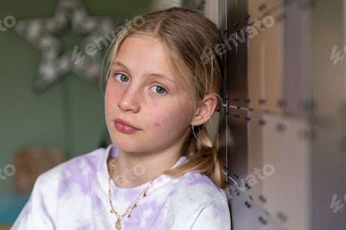 Preview: Moody young teenage girl leaning on wall portrait