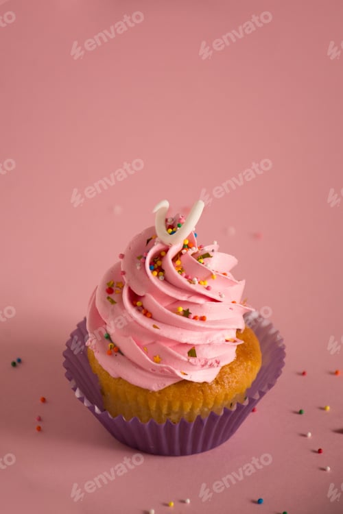 Preview: Appetizing cupcake with a pink frosting and decorative sprinkles on a pink surface