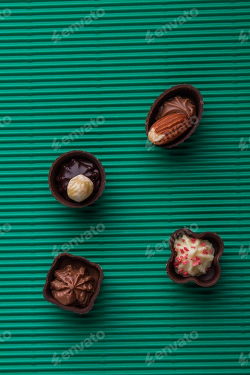 Preview: Assortment of brown pralines chocolate candies on green background.