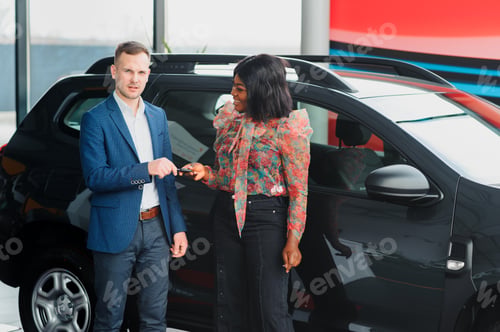 Preview: beautiful young african woman buying a car at dealership