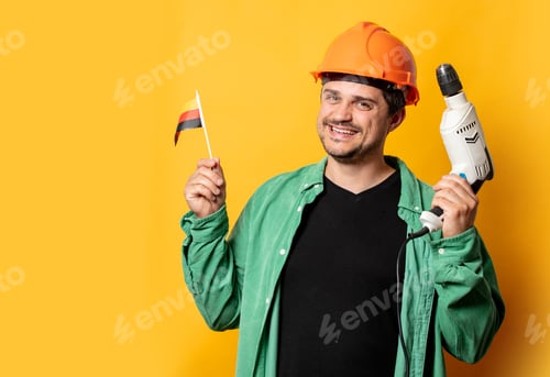 Preview: Guy in helmet with drill and German flag on yellow background