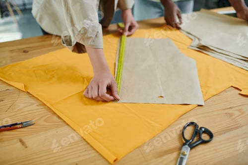 Preview: cropped view of creative multicultural fashion designers measuring sewing patterns in print studio