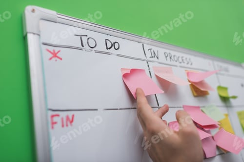 Preview: cropped view of businessman puting sticky note on task board