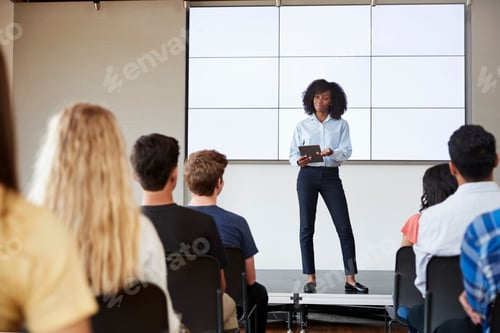 Preview: Female Teacher With Digital Tablet Giving Presentation To High School Class In Front Of Screen