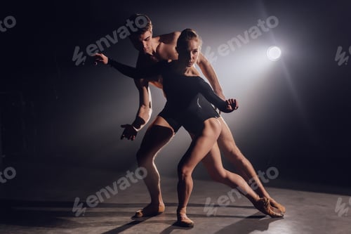 Preview: Beautiful young acrobats or gymnasts on floodlights background. Professional ballet couple dancing
