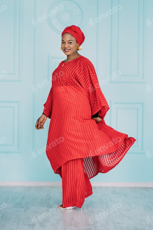 Preview: Full length portrait of smiling African woman dressed in stylish traditional ethnic red suit and