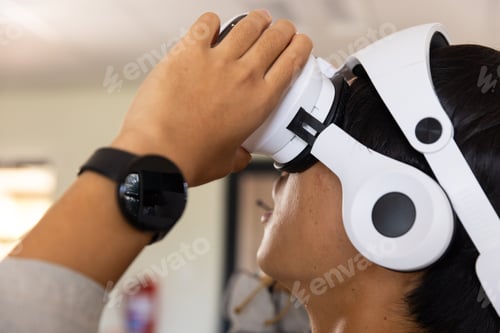 Preview: Using VR headset, asian teenage boy exploring virtual reality experience in school setting