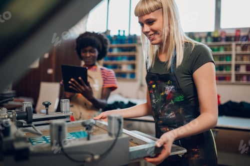 Preview: Smiling print shop worker adjusting printing plate on machine at facility