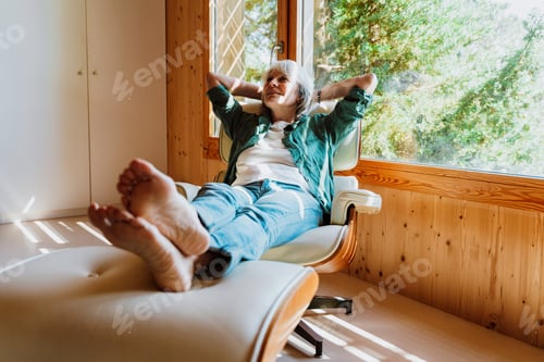 Preview: Senior woman relaxing in armchair enjoying nature view