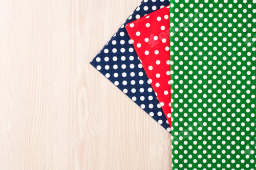 Preview: Polka dot fabric for sewing and needlework on wooden background. top view