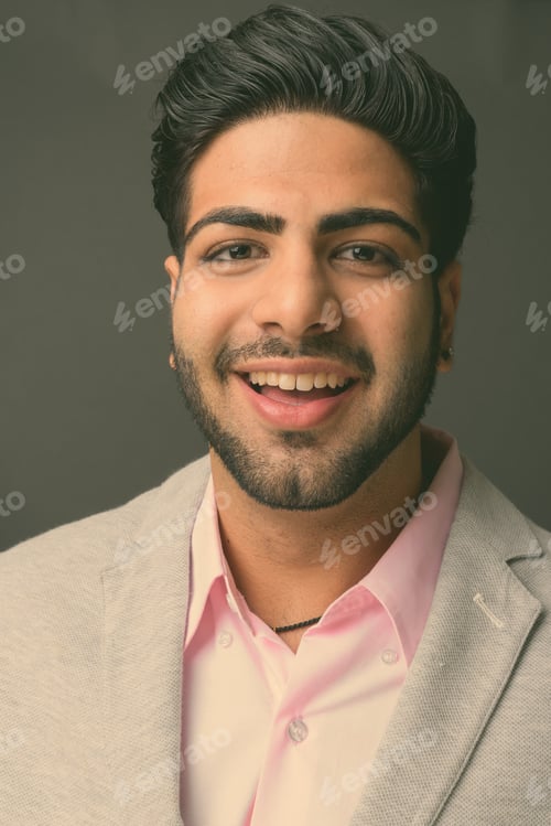 Preview: Young handsome Indian businessman against gray background
